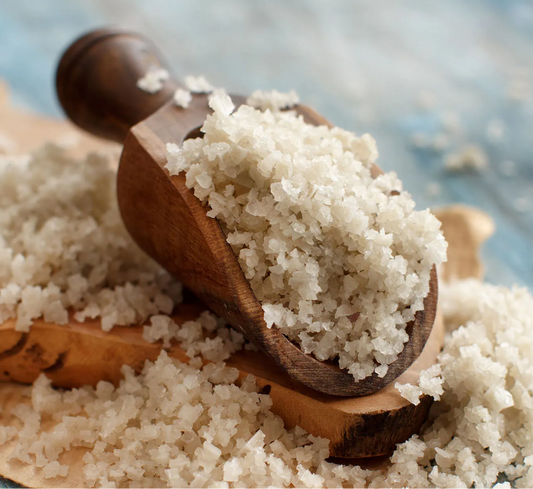 Wooden scoop filled with celtic salt on a blue wooden surface